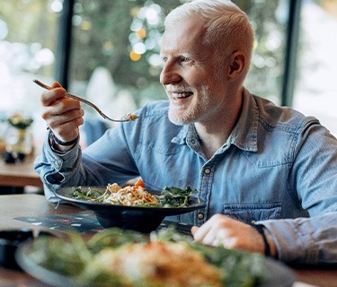 Man in denim jacket eating at a restaurant