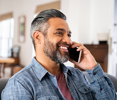 Man smiling while talking on phone at home