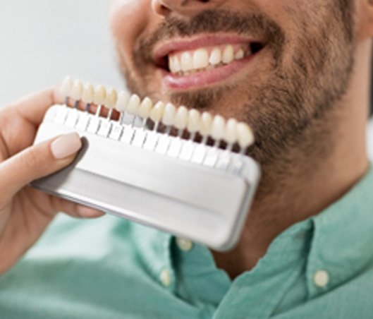 Man smiling next to shades of veneers