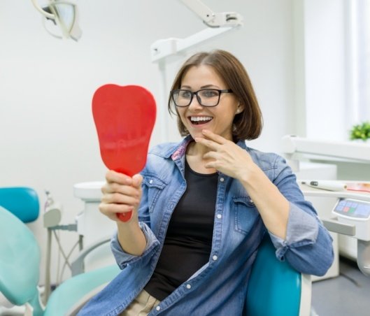 Young woman seeing her new smile after cosmetic dental bonding in Fort Worth