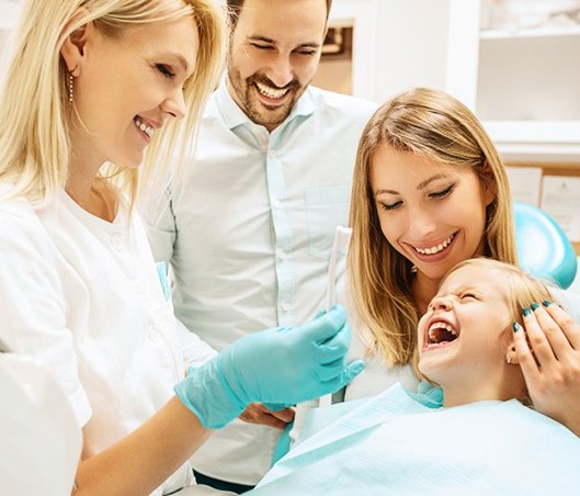parents and child smiling with their family dentist