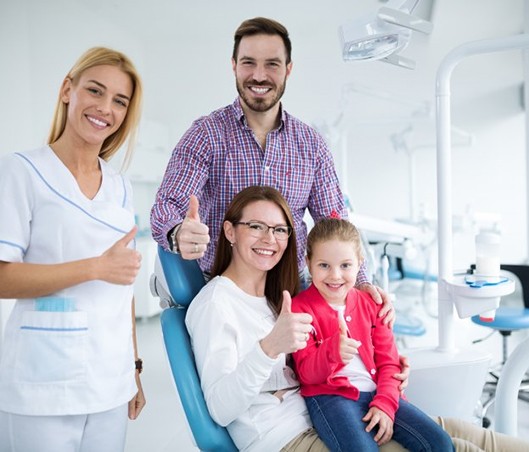 a dentist and a family giving a thumbs up