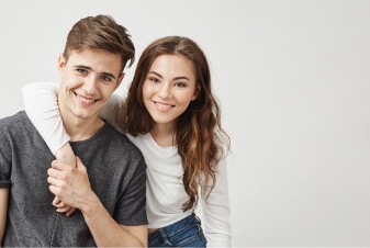Smiling young man and woman holding each other
