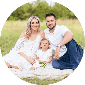 Fort Worth Texas dentist Doctor Rhiannon B Presley smiling with her husband and child sitting in grass