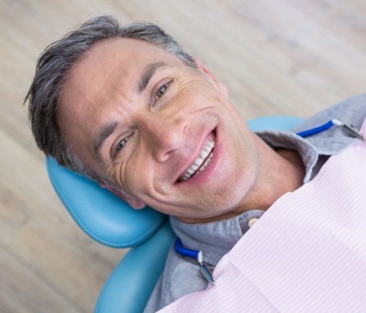 Older man in dental chair smiling after gum disease treatment in Fort Worth