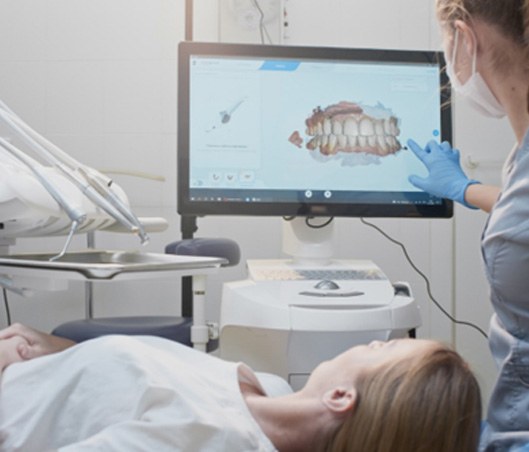 a dentist showing a patient a 3D model of their mouth