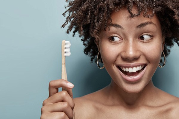 Woman holding and smiling at a toothbrush