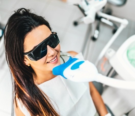 Smiling woman receiving professional teeth whitening in Fort Worth