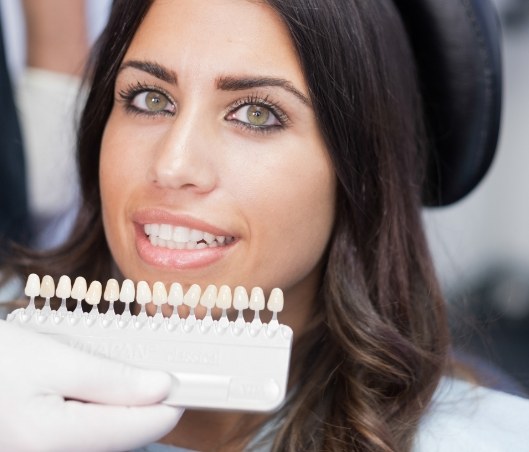 Woman in dental chair with shade guide to select the color of her dental veneers and crowns in Fort Worth