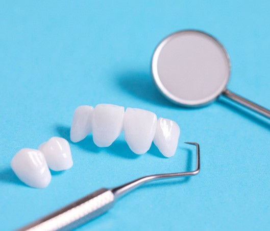 Veneers and dental instruments on a light blue background