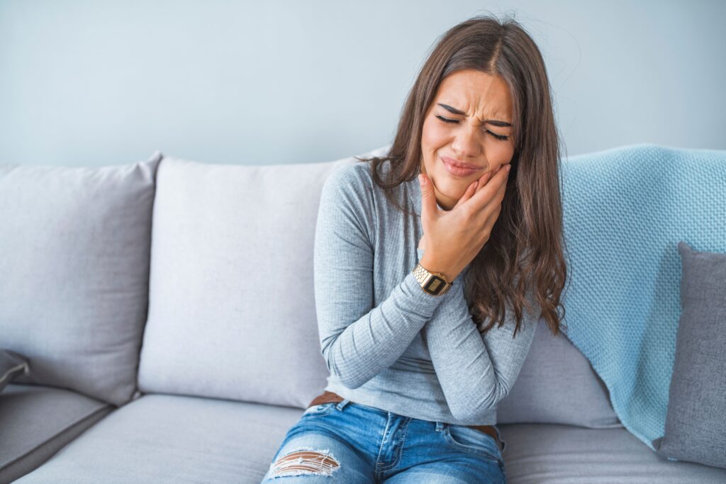 Woman on grey couch pressing both han